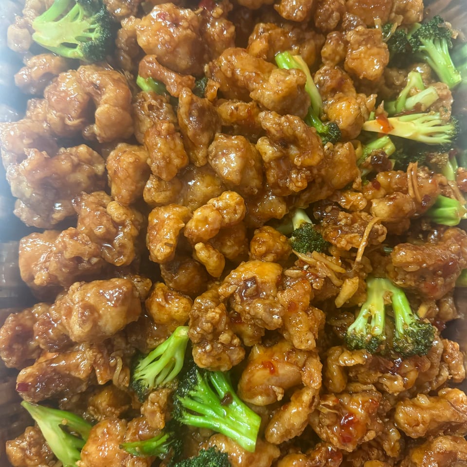 Glazed crispy chicken pieces mixed with bright green broccoli florets in a savory sauce.