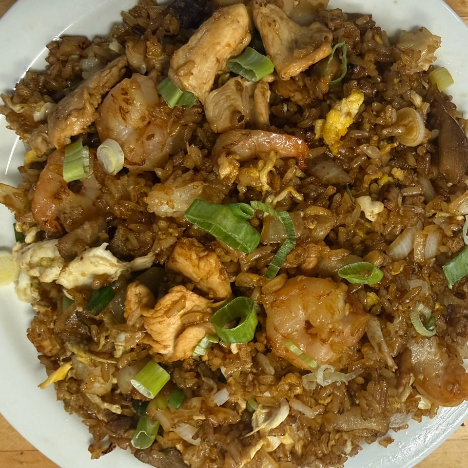 Plate of savory fried rice with shrimp, chicken, vegetables, egg, and sliced green onions.
